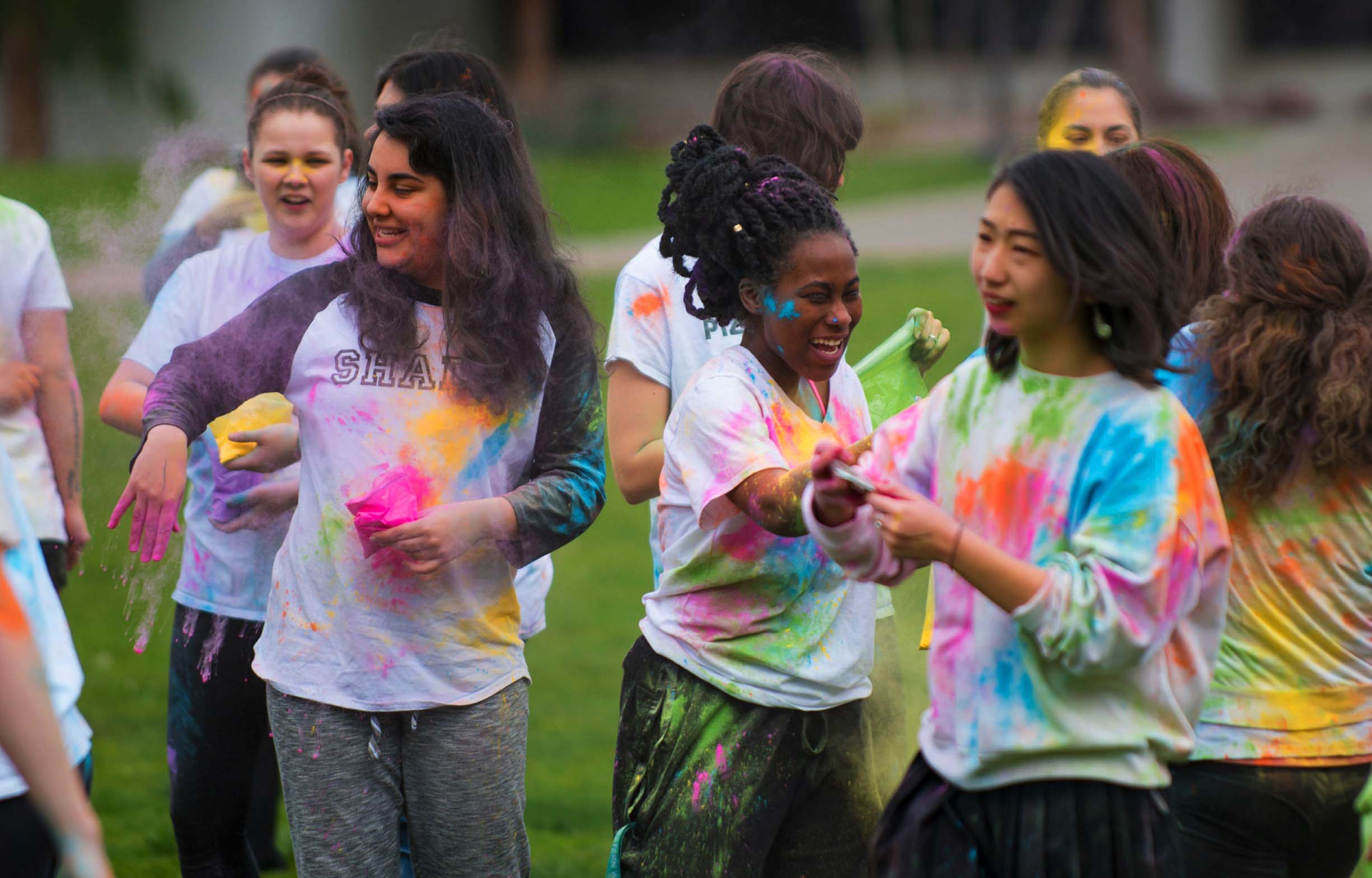 A group of students covered in colorful chalk in celebration of Holi
