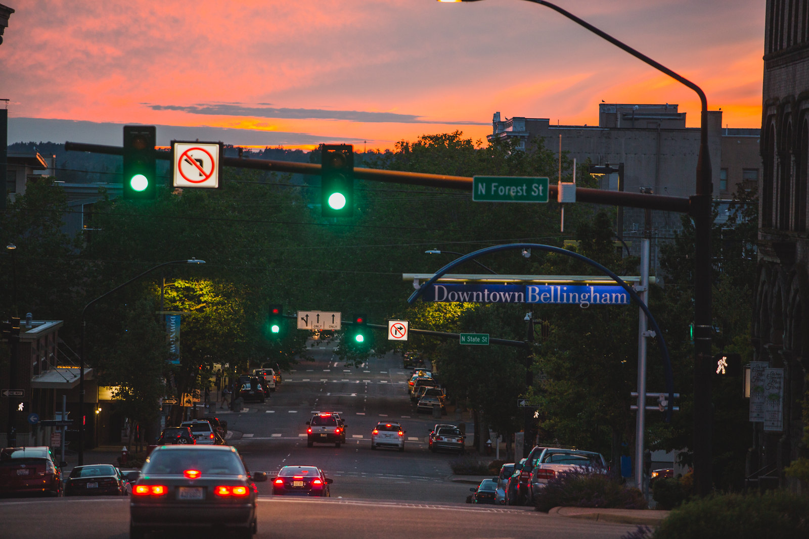 Holly Street in Bellingham at sunset. There are only a few cars on the road and all the traffic lights are green.