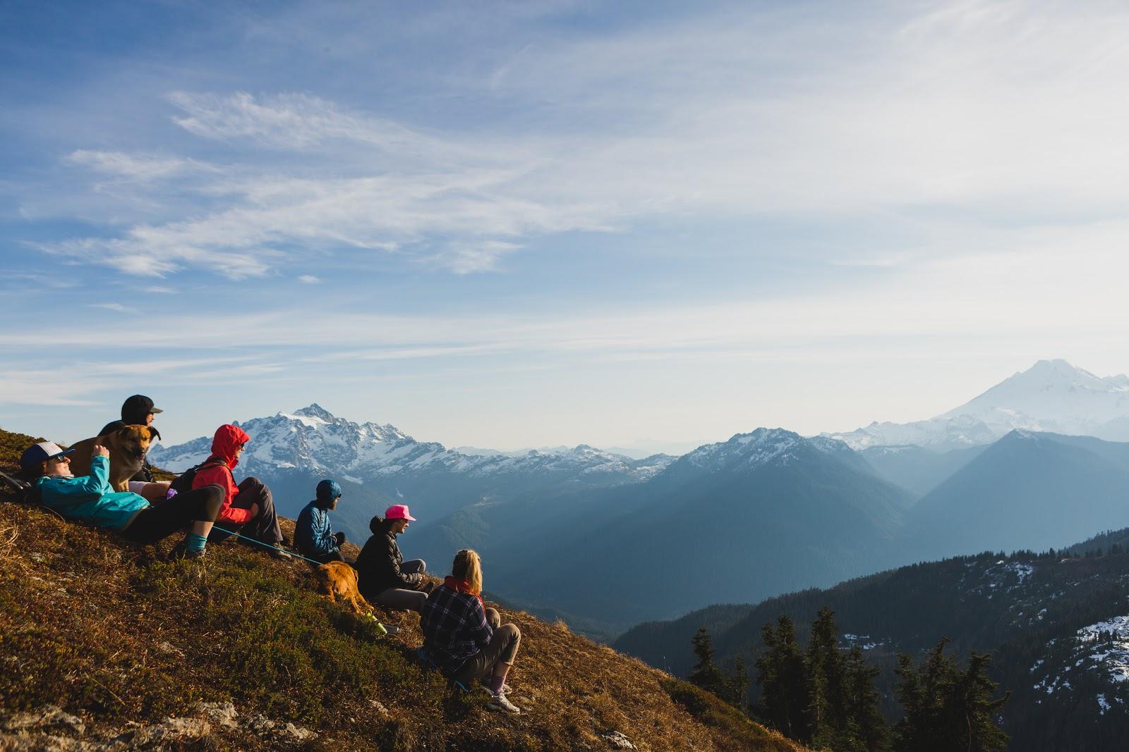 Students relax on a hill and take in a view of a mountain range