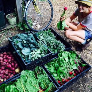 A student posing with their harvest of veggies and greens