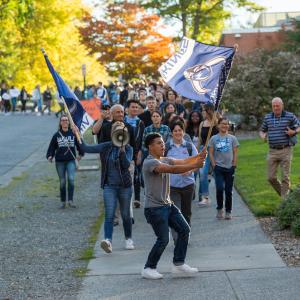 First-Year students are led by a WWU flag carrying student as they march towards downtown Bellingham for the annual Paint B'ham Blue event.