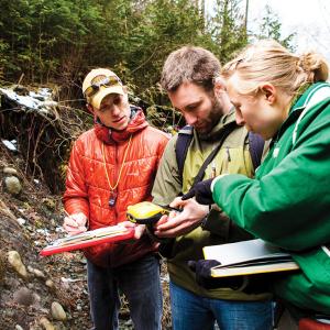 Three geology students working together in the field.