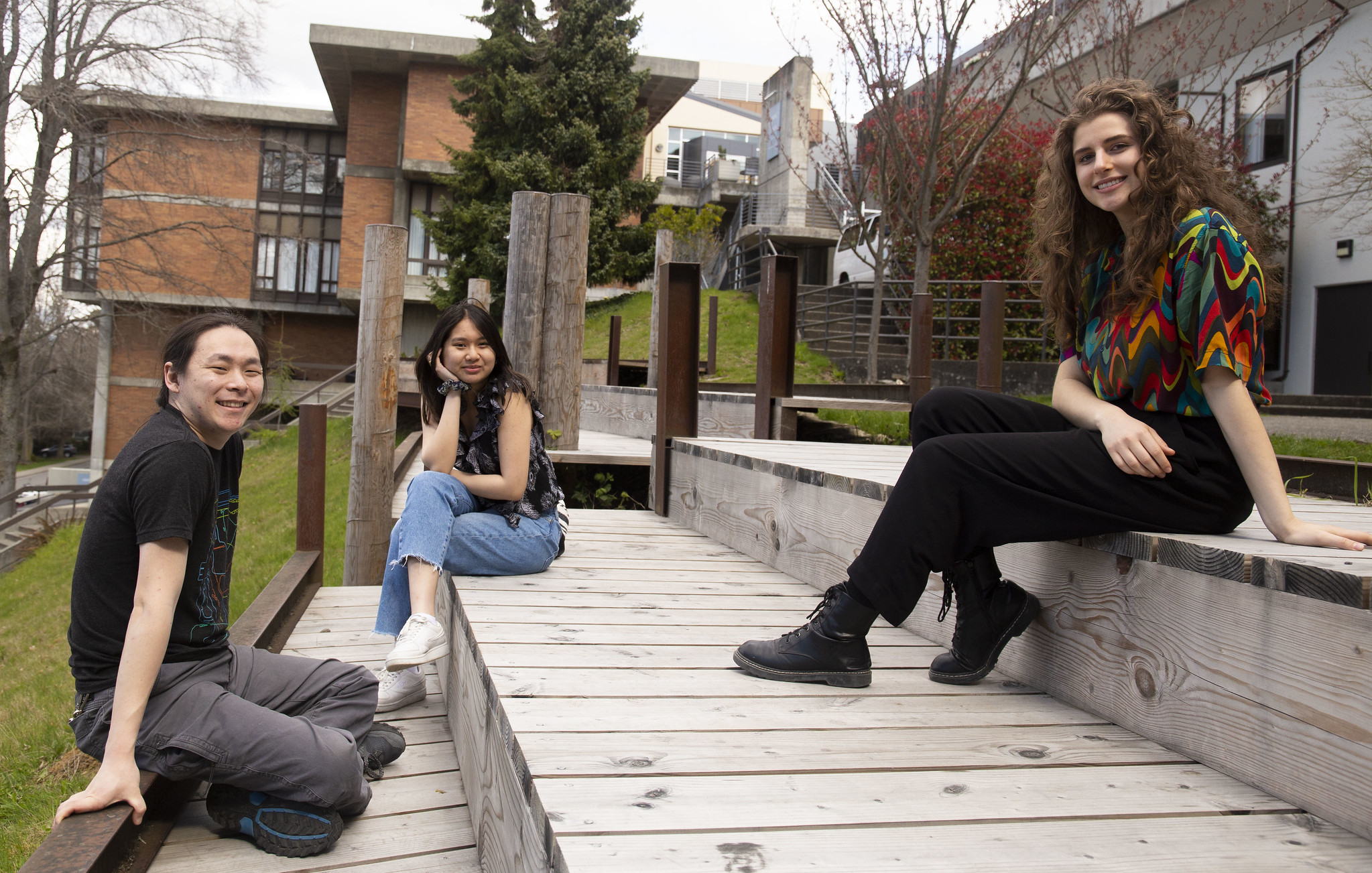 Three people sitting in an outdoor sitting area on campus
